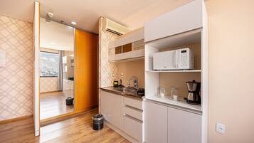 A modern kitchen with white cabinetry, a built-in microwave, and a coffee maker.