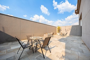 An outdoor patio with stone flooring, metal chairs, and a round table. - Flat Osasco Trade (Osasco)