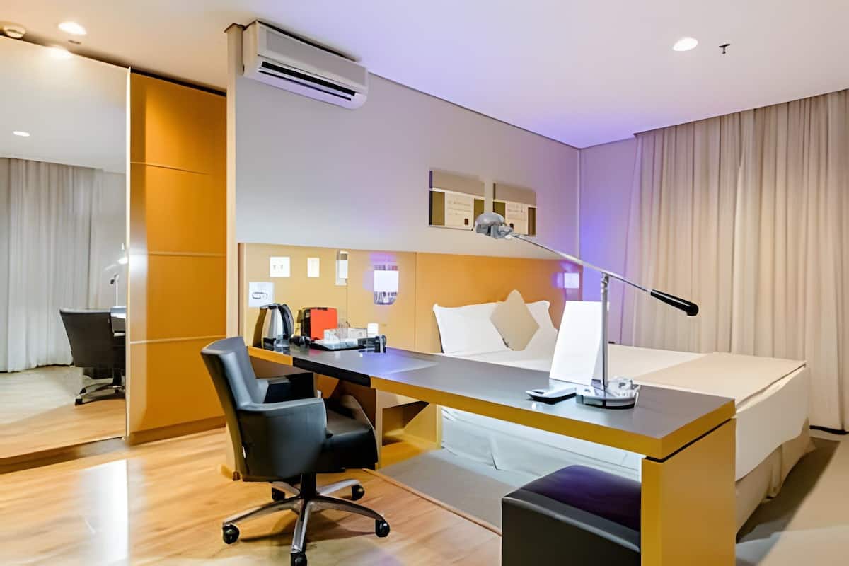Ein Hotelzimmer mit Bett, Schreibtisch, Stuhl und Klimaanlage.