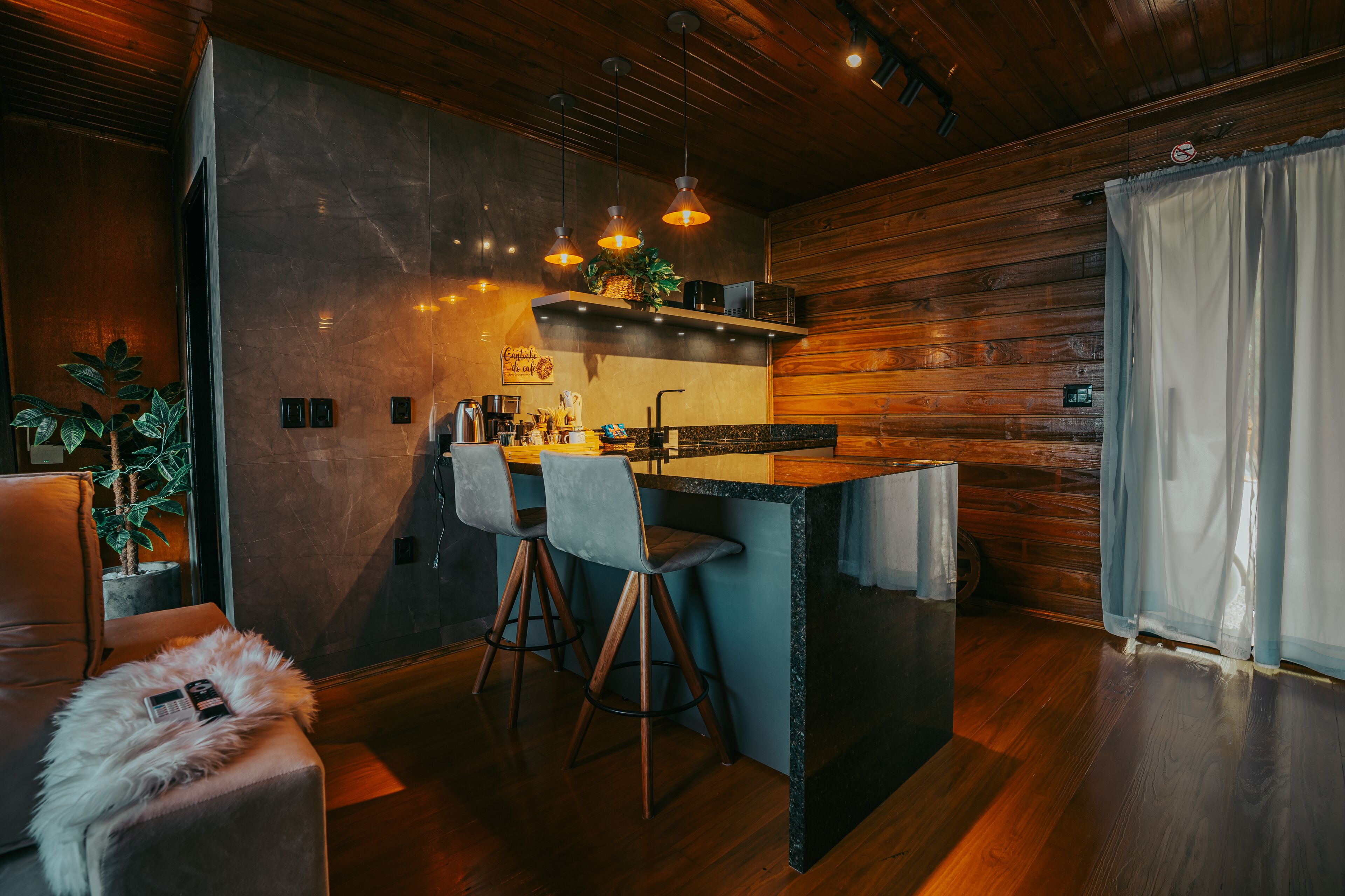 Une cuisine moderne avec un coin bar, des murs en bois et des luminaires suspendus.
