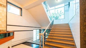 A staircase with a wooden finish and a metal railing, leading to an upper floor. - Treebo Raval Resort with Valley View (Wai)
