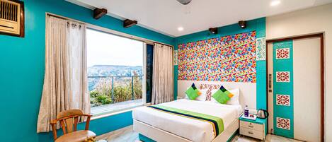 Un dormitorio con cama, una silla, una mesa, una ventana con cortinas y vistas al exterior.