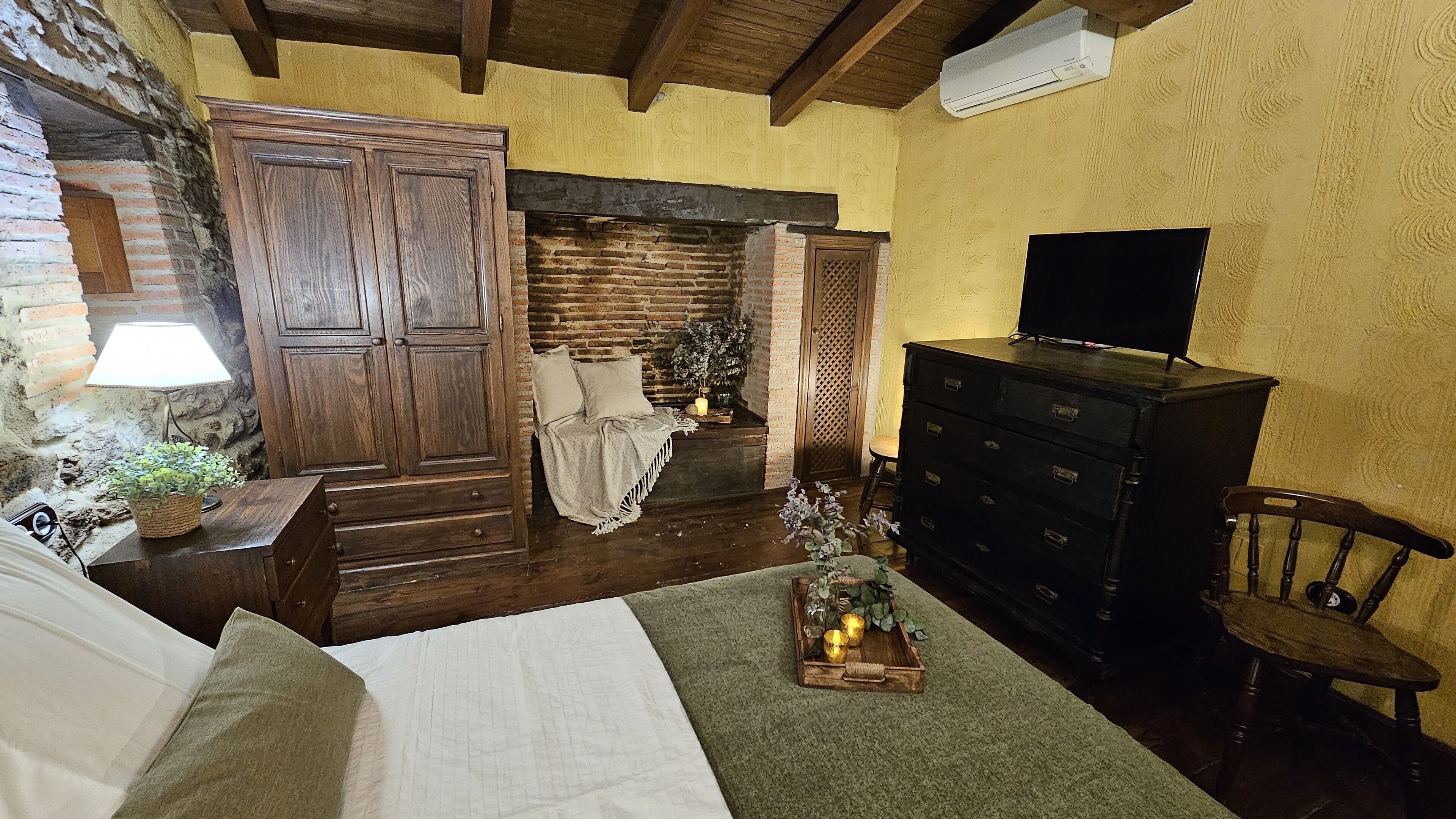 Una habitación acogedora con una cama, un aparador, un televisor y una silla de madera.
