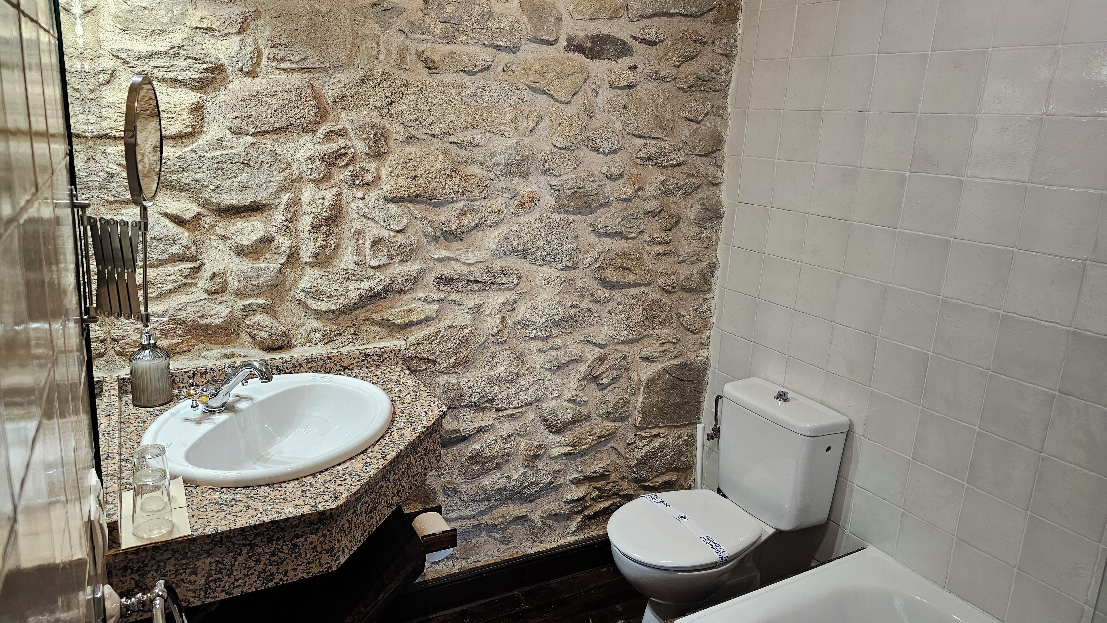 A bathroom with a stone wall, a sink, and a toilet.
