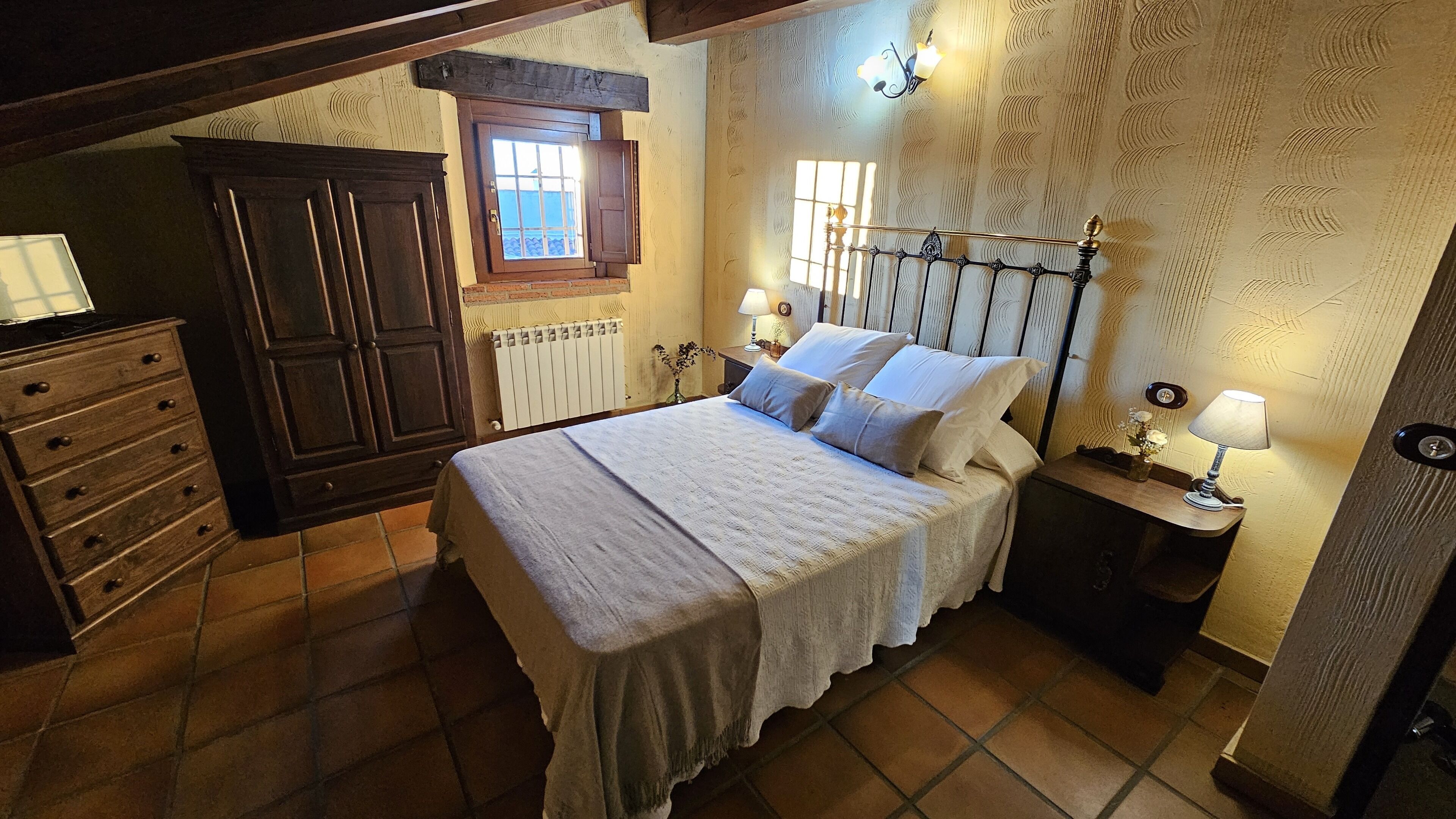 Una camera da letto con un letto, una cassettiera, comodini e una finestra.