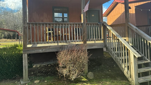 Eine Holzhütte mit Veranda, einem kleinen Busch und einer Flagge.