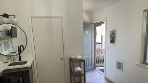 Ein Badezimmer mit Waschbecken, Spiegel und Toilettenartikeln. Eine Tür führt zu einem Balkon mit Geländer.