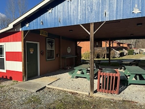 Un bâtiment à la façade rayée de rouge et de blanc, avec une enseigne indiquant « SALLE DE JEUX » et des sièges à l’extérieur, sous un auvent bleu.