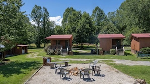 Ein Campingplatz mit Holzhütten, einer Feuerstelle und Sitzgelegenheiten im Freien.