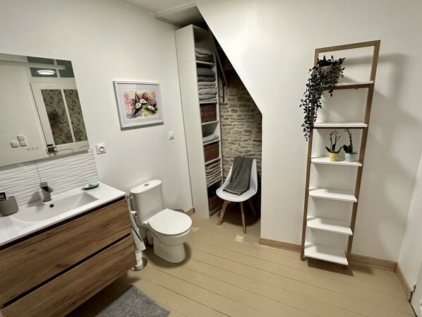 Ein modernes Badezimmer mit einem Holzkosmetikschrank, einer Toilette, einer Duschkabine und einer eingebauten Ablage mit Pflanzen.