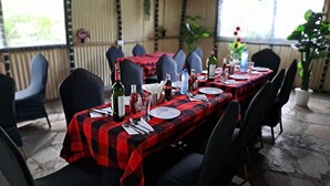 Een restaurant met terras, rode en zwarte geruit tafelkleed en zwarte stoelen.