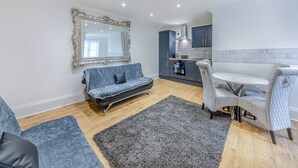 Un salon moderne comprenant un canapé, une table à manger et un coin cuisine.