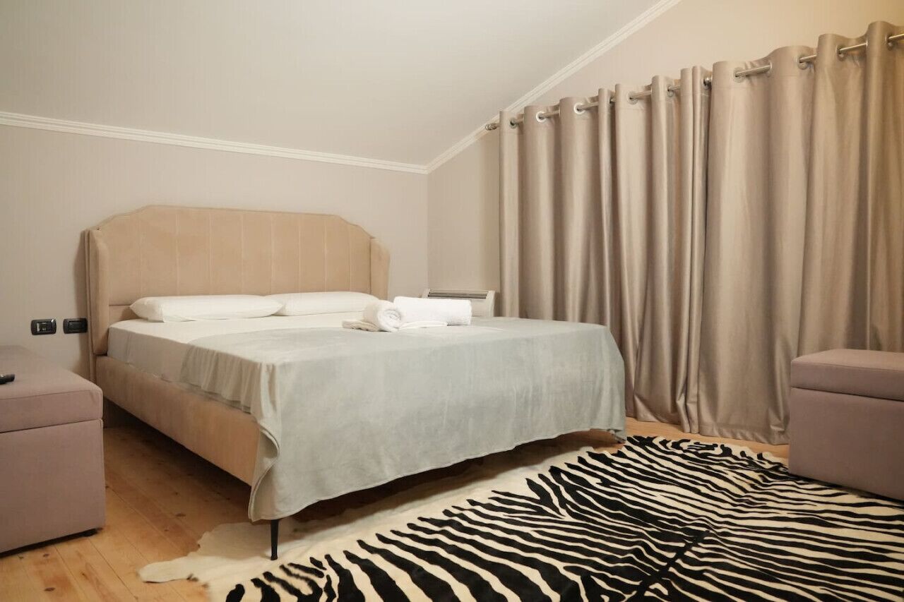 Une chambre à coucher avec un lit, une table de chevet, une chaise et un tapis à motifs zébrés.