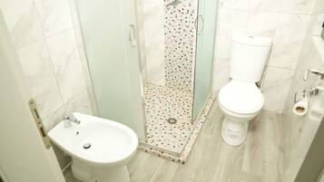 Ein Badezimmer mit Dusche, Toilette und Bidet.