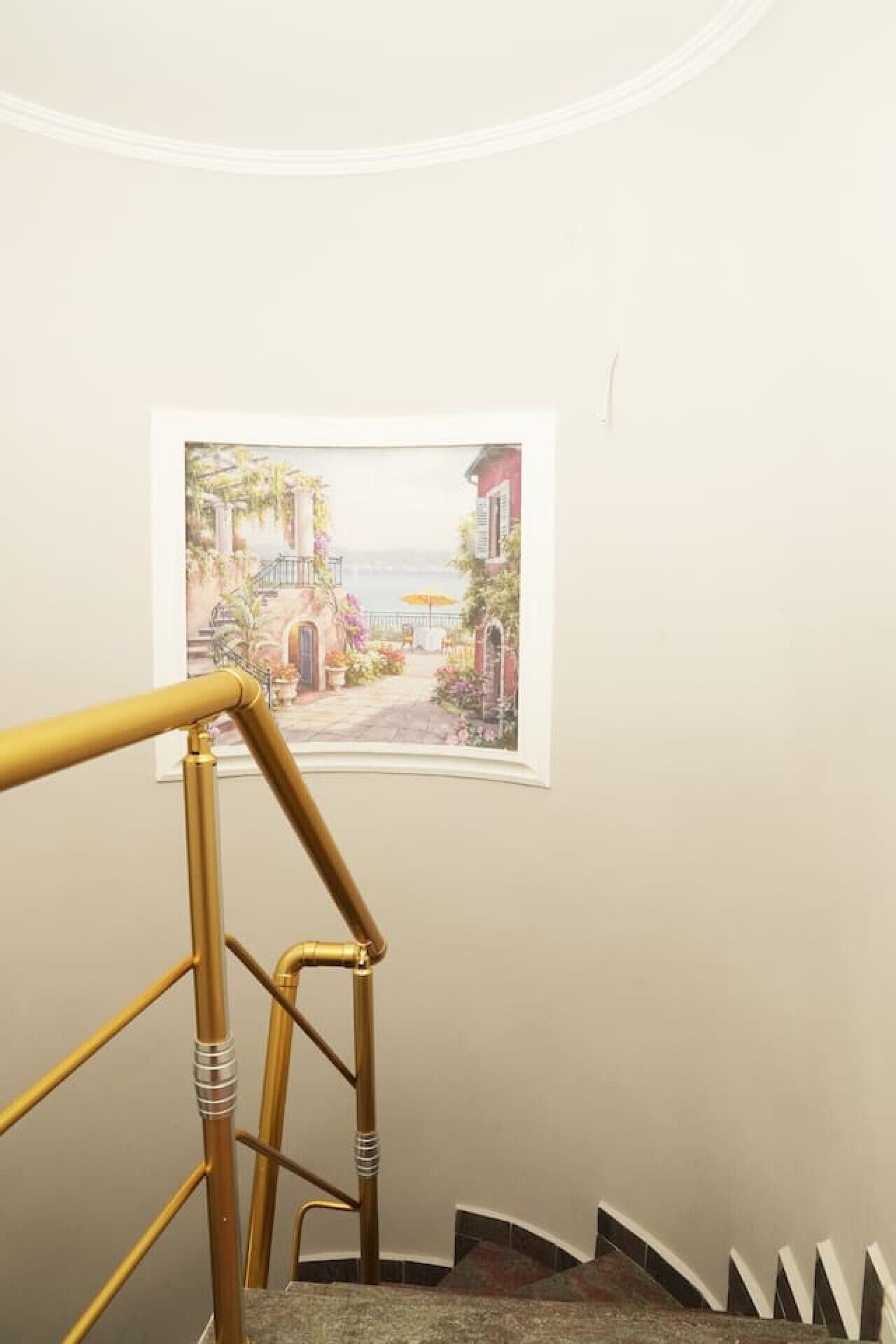 A staircase with a handrail and a framed picture of a coastal scene on the wall.