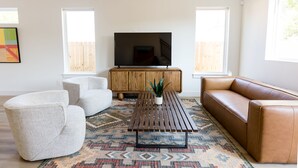 Un salon avec un canapé, des fauteuils, une table basse et un téléviseur.