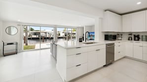 Una cucina moderna con mobili bianchi, lavastoviglie e una grande isola.