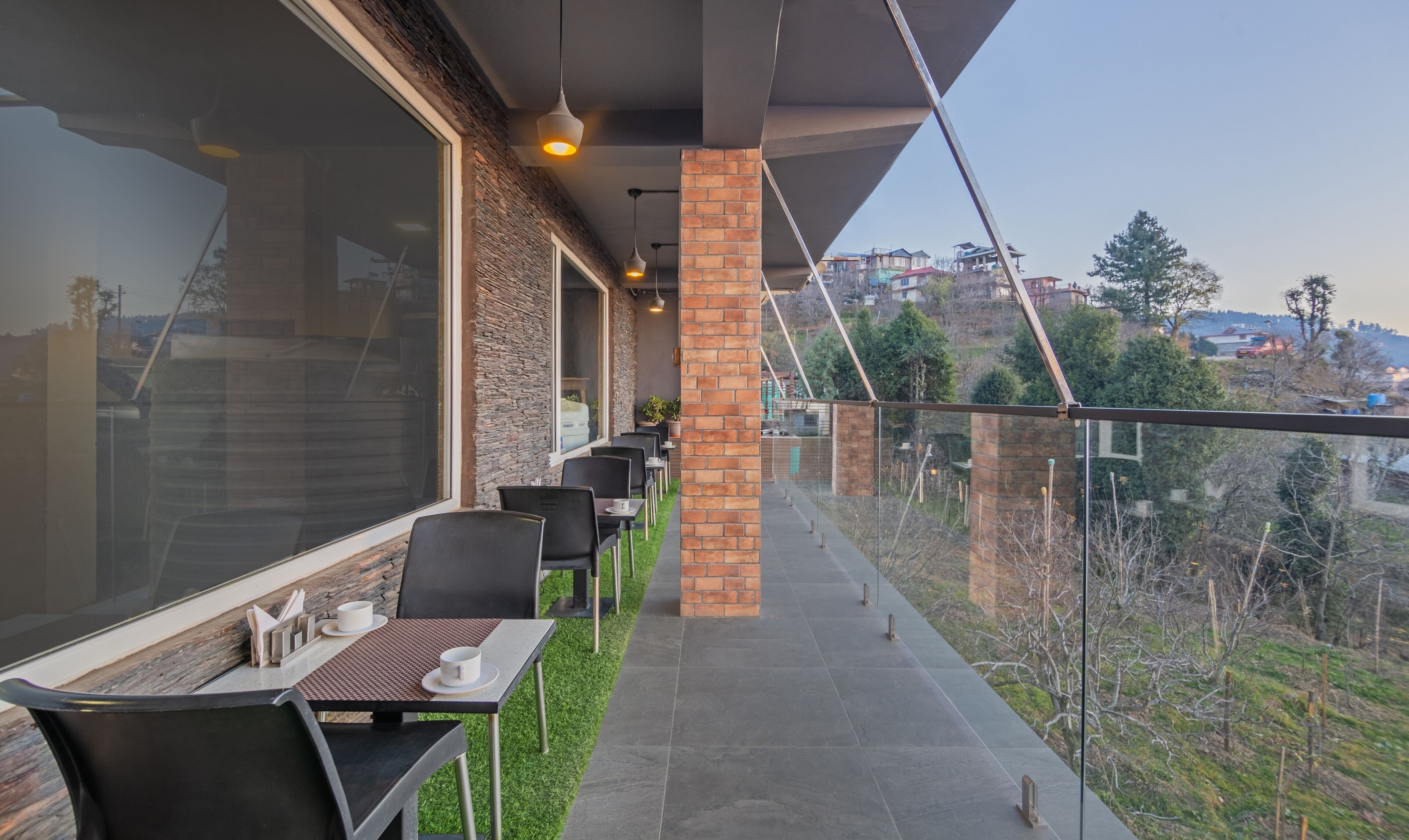 Un espace extérieur aménagé avec des tables et des chaises, un pilier en briques et une vue sur une colline.