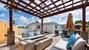 Un patio techado con mobiliario exterior, una chimenea y un pérgola.