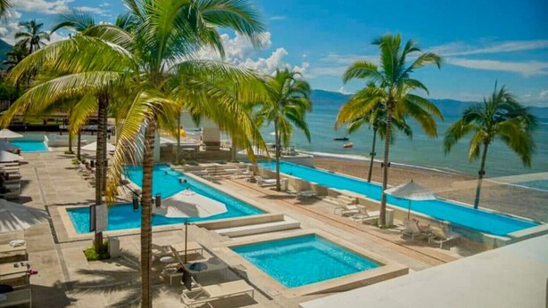A resort with multiple swimming pools, palm trees, and a beach view. - Chic Oceanfront Studio Loft – Unique Art & Views (Puerto Vallarta)