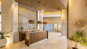A reception area with a wooden reception desk, a decorative wall, and potted plants. - Chic Oceanfront Studio Loft – Unique Art & Views (Puerto Vallarta)