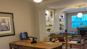 Ein Essbereich mit einem Holztisch und Stühlen, einer Kandelaber und einem Bücherregal mit Dekoration.