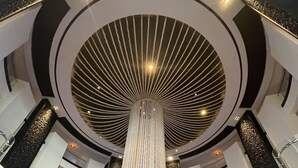 En modern entréhall med en central pelare, högt i tak och utsikt över gatan utanför.
