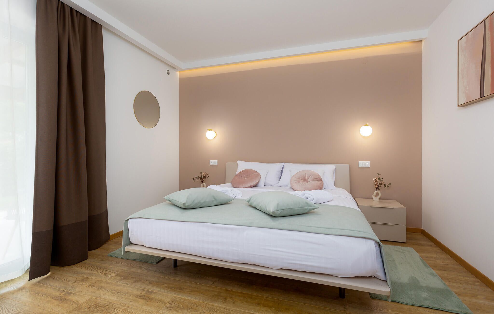 A bedroom with a bed, bedside tables, a wall-mounted light, and a window with curtains.
