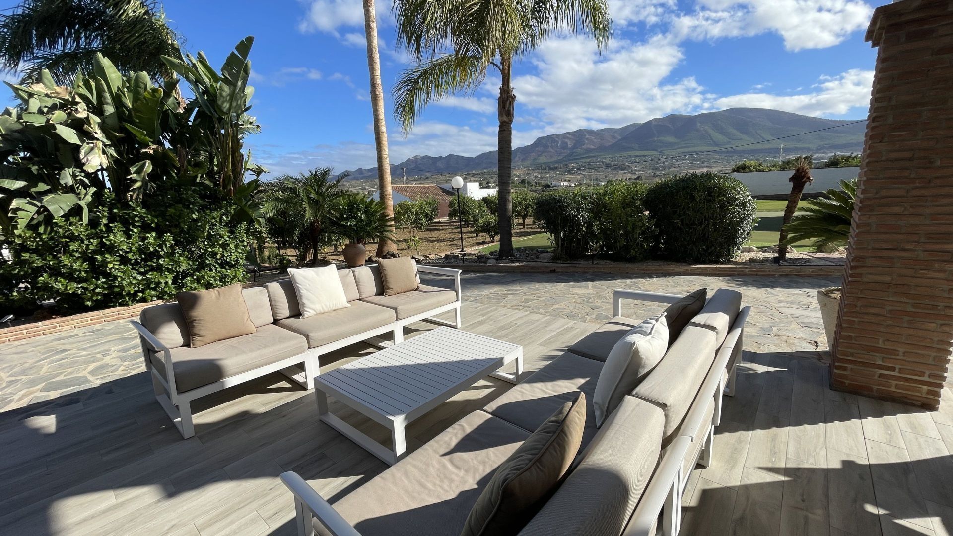 Un patio al aire libre con un sofá, sillas y una mesa.