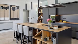 Une cuisine moderne dotée d’un îlot central, de tabourets de bar, d’une bibliothèque intégrée et d’une grande fenêtre.