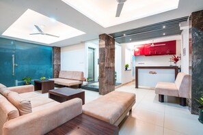 A modern hotel lobby with a seating area, a reception desk, and a kitchen in the background. - Treebo Silver Apartment (Nagpur)