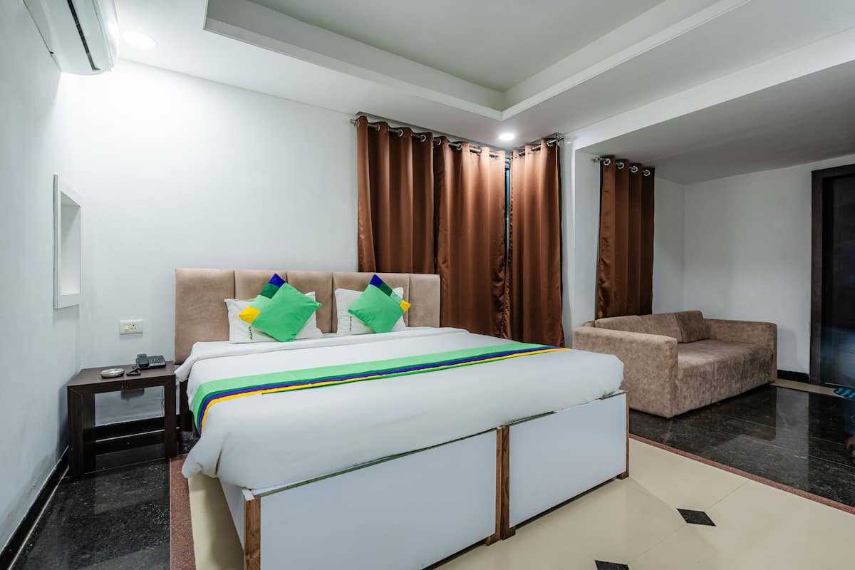 A hotel room with a bed, a nightstand, a chair, and curtains.