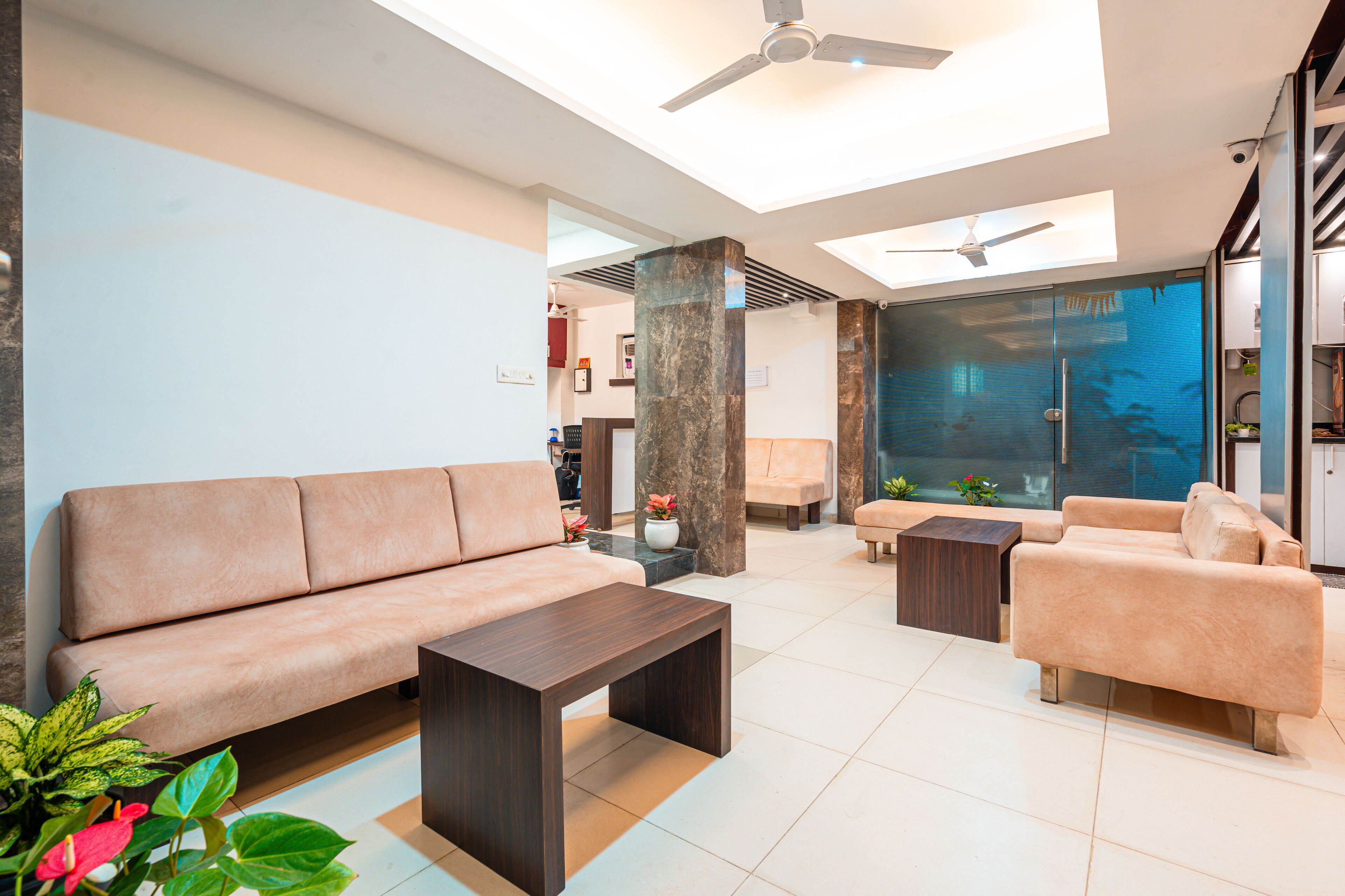 A modern living room with a sofa, armchairs, a coffee table, and a glass partition.