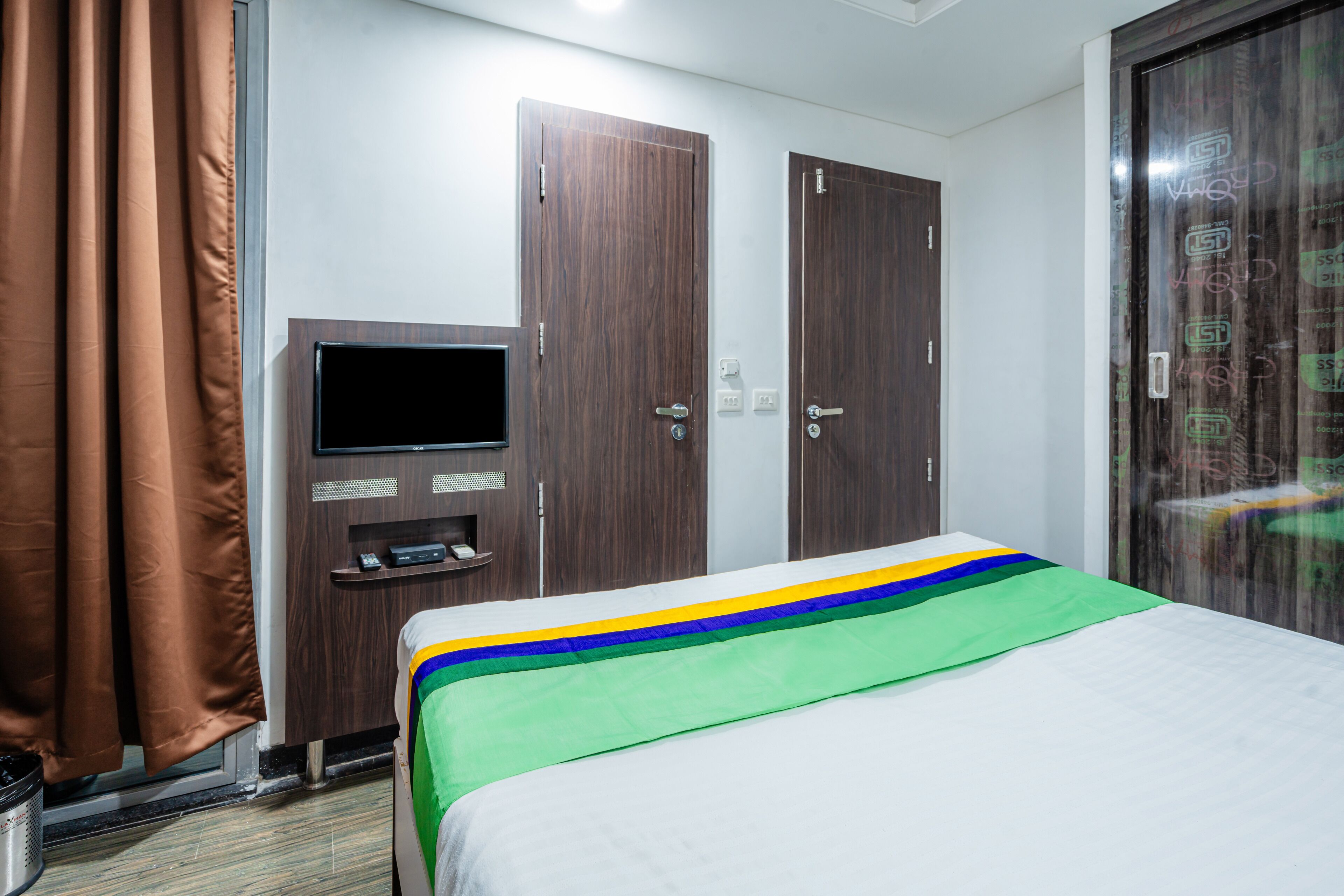 A hotel room with a bed, a TV, a wardrobe, and a curtain.