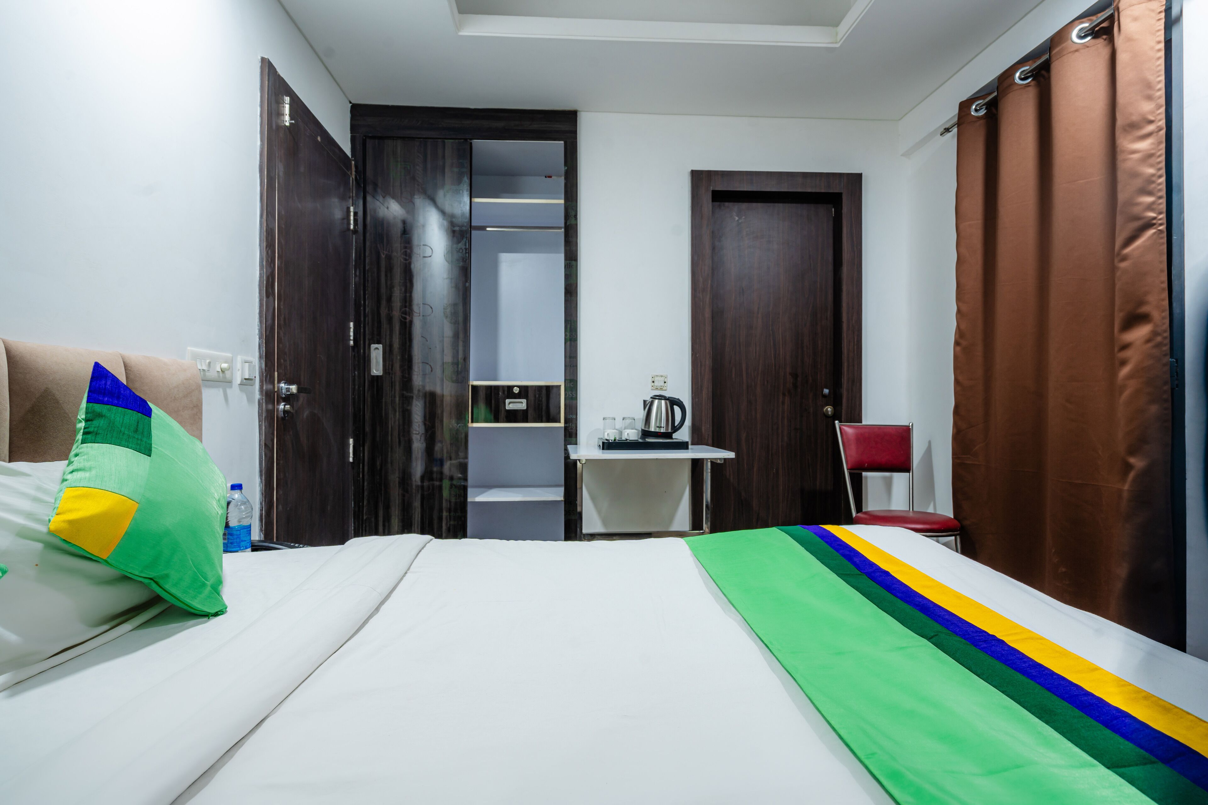 A hotel room with a bed, a desk, a chair, and a bathroom visible through an open door.