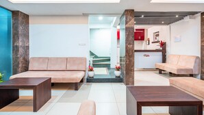 Un vestíbulo moderno con mostrador de recepción, dos sofás y una mesa de centro.
