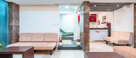 A modern lobby with a reception desk, two sofas, and a coffee table.