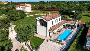 Une villa moderne dotée d’une piscine, d’un patio couvert et d’un jardin.