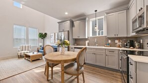 Una cocina moderna con armarios grises, una mesa de comedor de madera y un horno empotrado.