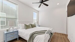 Un dormitorio con cama, mesita de noche, lámpara y ventilador de techo.