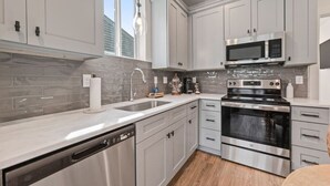 Una cocina moderna con electrodomésticos de acero inoxidable, armarios blancos y lavavajillas.