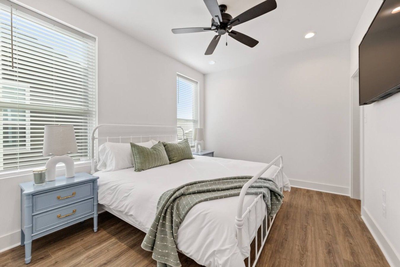 A bedroom with a bed, nightstand, lamp, and ceiling fan.