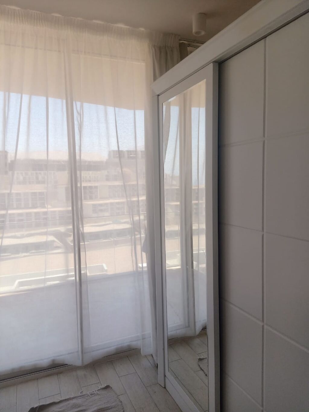 A room with a large sliding glass door, a view of a parking lot, and a tiled floor.