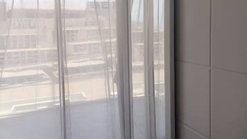 A room with a large sliding glass door, a view of a parking lot, and a tiled floor.