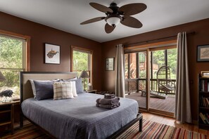 A bedroom with a large bed, a ceiling fan, a view of the outdoors, and a balcony with a hanging chair. - Entire Cabin in Lost River w/ fire pit + pet friendly! (Lost River)