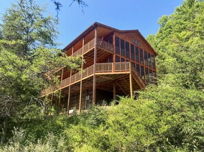 A multi-story wooden cabin with a balcony and stairs, surrounded by dense greenery. - Entire Cabin in Lost River w/ fire pit + pet friendly! (Lost River)