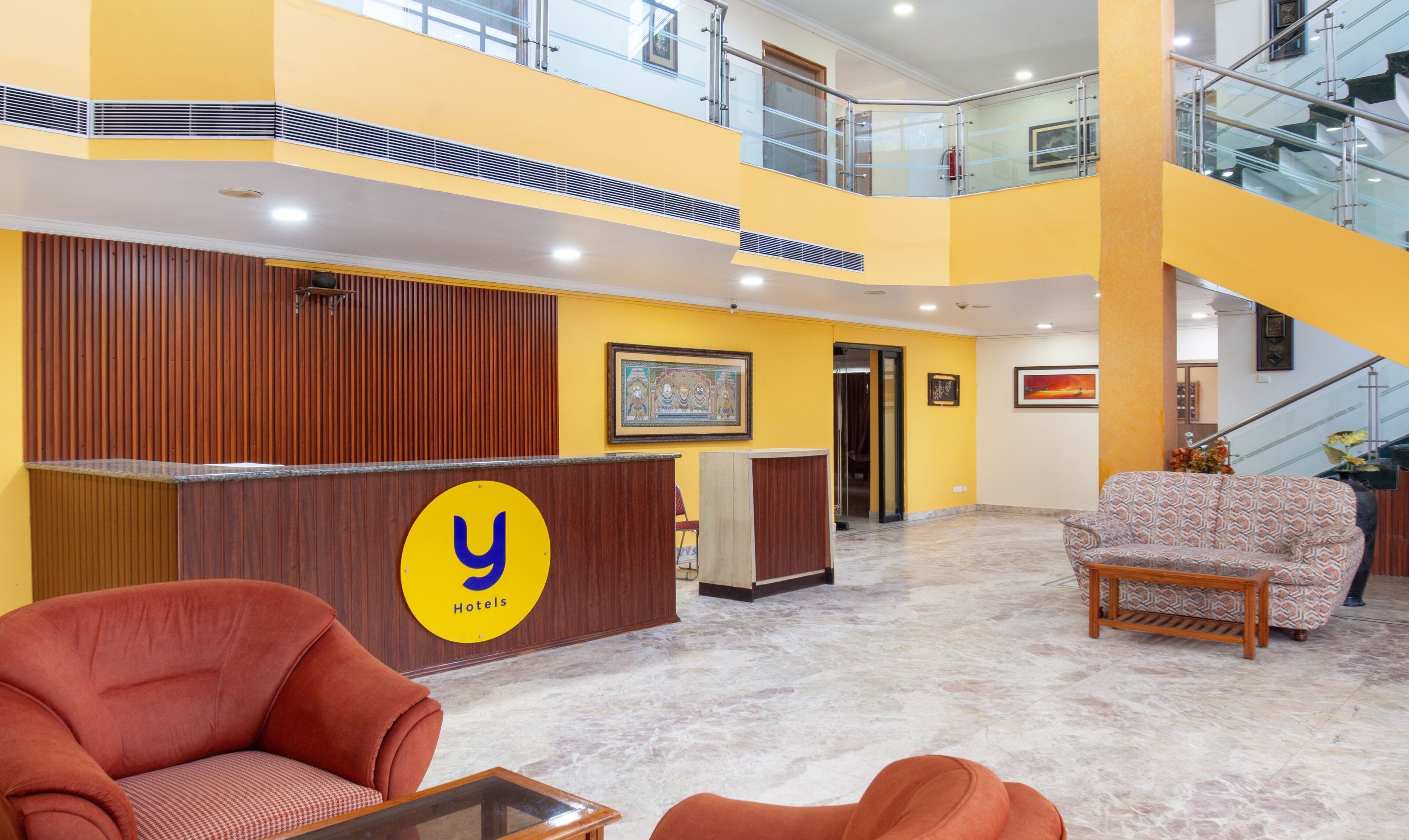 A hotel lobby with a reception desk, a staircase, and seating areas.