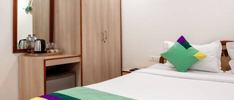 Una habitación de hotel con cama, mesita de noche, armario y espejo.