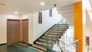 Uma escadaria moderna com guarda-corpos de vidro e piso de mármore.