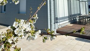 Uma casa moderna com varanda coberta e jardim com flores vibrantes.
